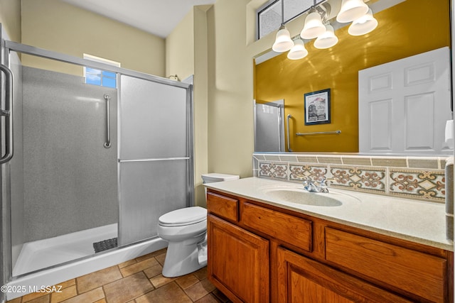 bathroom featuring toilet, a stall shower, and vanity