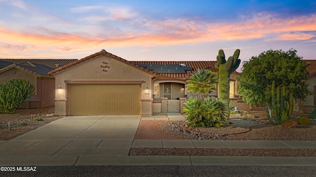 mediterranean / spanish-style home with a garage, concrete driveway, solar panels, a tile roof, and stucco siding