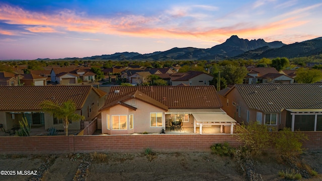 back of house featuring stucco siding, fence, a mountain view, a residential view, and a tiled roof