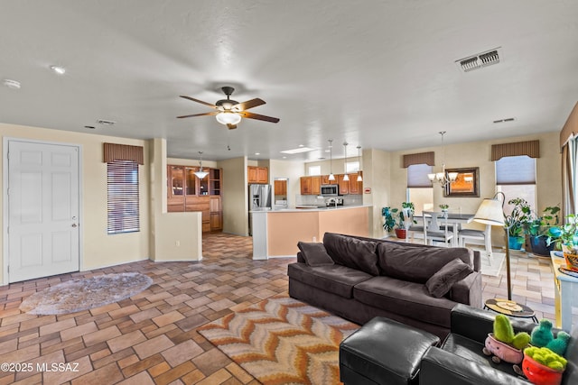 living room with visible vents and ceiling fan with notable chandelier