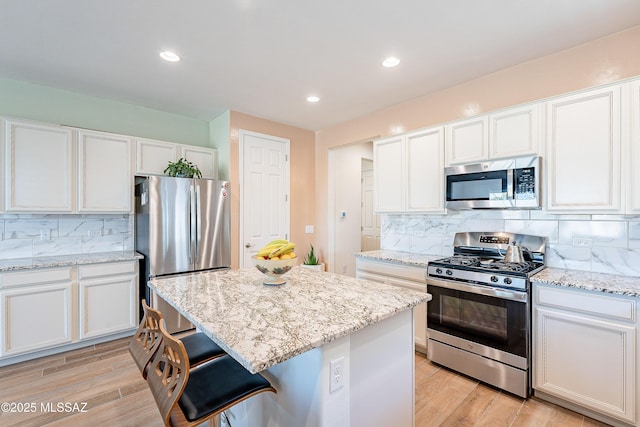 kitchen with appliances with stainless steel finishes, white cabinets, and light wood-style floors