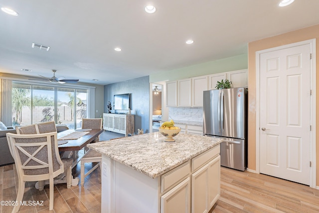 kitchen featuring a kitchen island, visible vents, light wood-style floors, open floor plan, and freestanding refrigerator