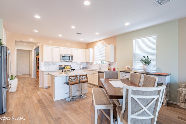 kitchen featuring white cabinets, appliances with stainless steel finishes, visible vents, and a center island