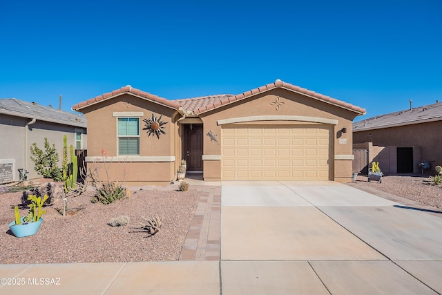 view of front facade with a garage, concrete driveway, a tiled roof, fence, and stucco siding