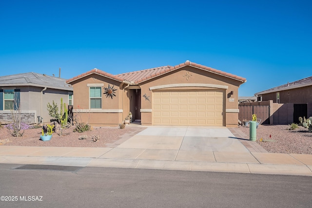 view of front of house with an attached garage, fence, a tile roof, concrete driveway, and stucco siding