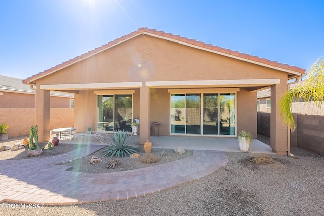 rear view of property featuring fence, a patio, and stucco siding