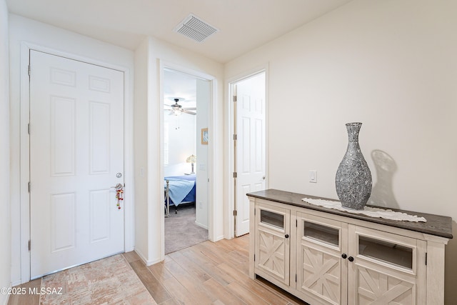 corridor featuring light wood-style flooring and visible vents