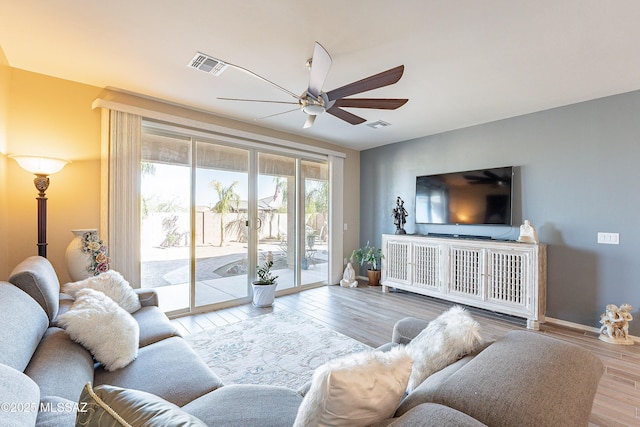 living area with a ceiling fan, visible vents, baseboards, and wood finished floors