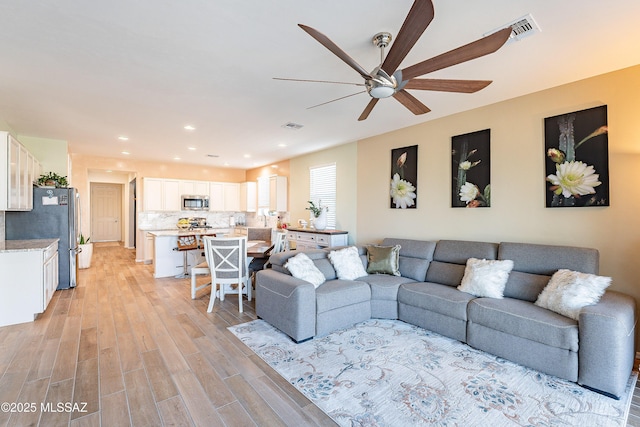 living area featuring light wood finished floors, recessed lighting, visible vents, and a ceiling fan