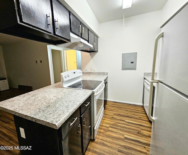 kitchen with white appliances, electric panel, baseboards, wood finished floors, and under cabinet range hood