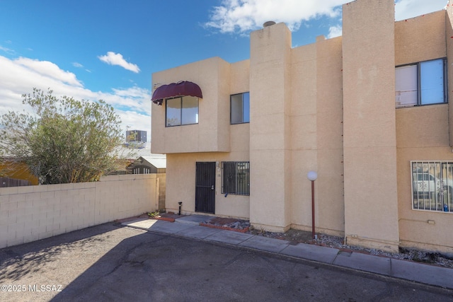 view of front facade with a patio area, fence, and stucco siding