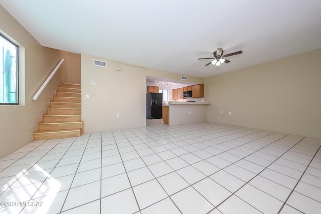 unfurnished living room featuring stairs, light tile patterned floors, visible vents, and a ceiling fan