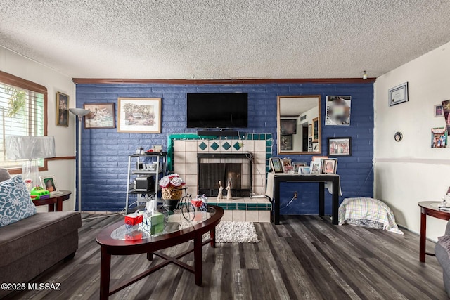 living room with a textured ceiling, wood finished floors, and a tile fireplace