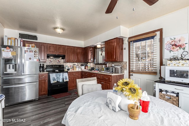 kitchen featuring light countertops, black electric range oven, backsplash, stainless steel fridge, and under cabinet range hood