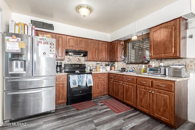 kitchen with stainless steel fridge, tasteful backsplash, black / electric stove, light countertops, and under cabinet range hood