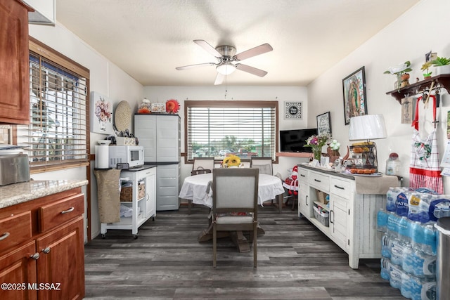 kitchen with white microwave, dark wood finished floors, and brown cabinetry