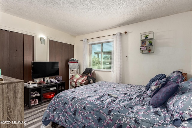 bedroom featuring a textured ceiling, two closets, and wood finished floors