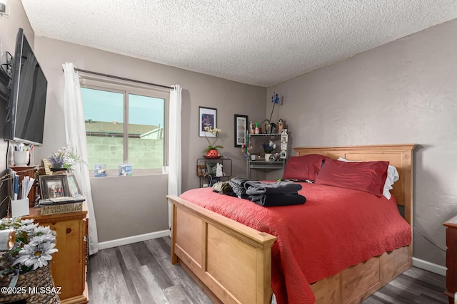 bedroom with a textured ceiling, wood finished floors, and baseboards