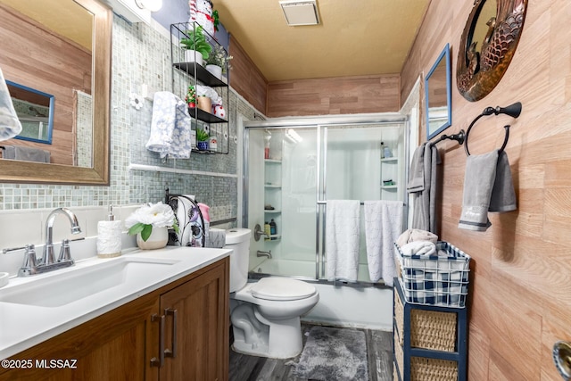 full bathroom with backsplash, shower / bath combination with glass door, vanity, and toilet