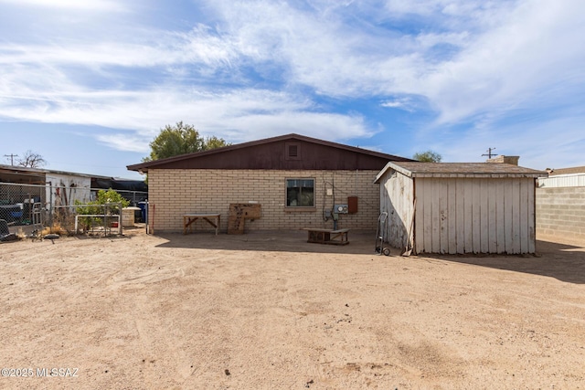 back of house with an outbuilding, brick siding, fence, and a shed