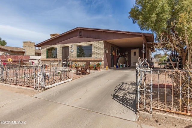 view of front facade featuring a carport, driveway, brick siding, and fence