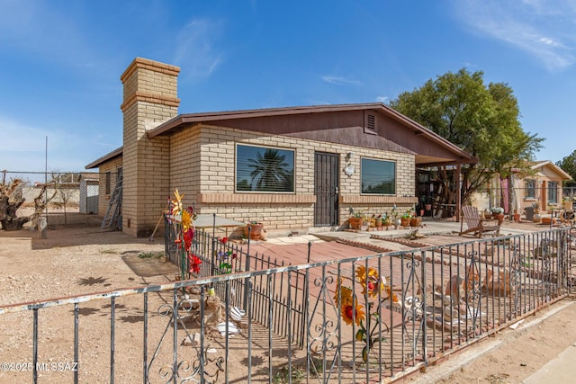 view of front of property featuring fence private yard, a chimney, and brick siding