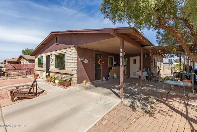 back of property featuring fence, an attached carport, concrete driveway, and brick siding