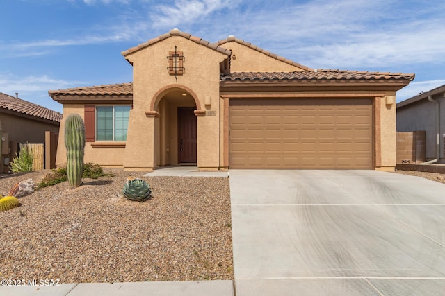 mediterranean / spanish-style house with a garage, concrete driveway, a tile roof, and stucco siding