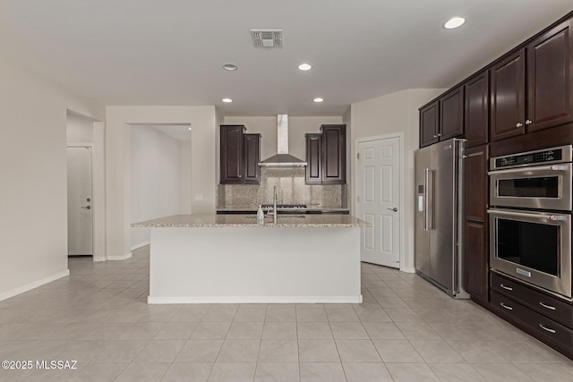 kitchen with stainless steel appliances, visible vents, dark brown cabinets, backsplash, and wall chimney exhaust hood