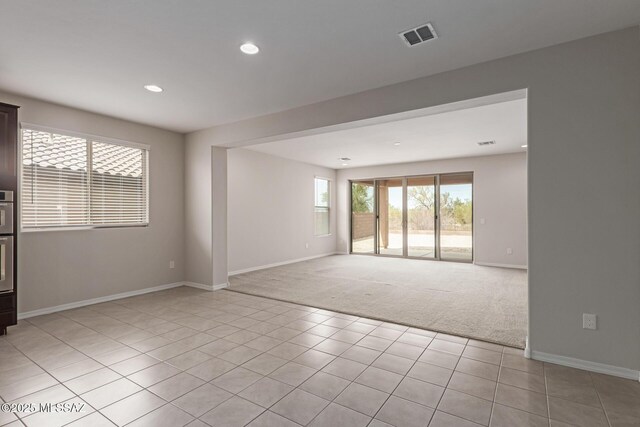 empty room with baseboards, visible vents, light colored carpet, light tile patterned flooring, and recessed lighting