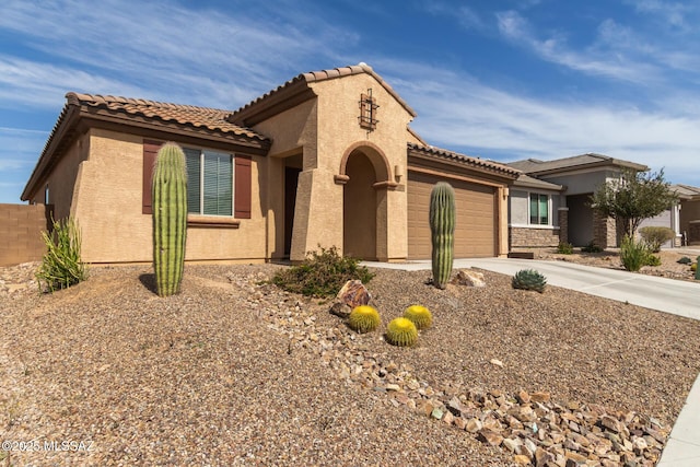 mediterranean / spanish-style house with a garage, concrete driveway, a tile roof, and stucco siding