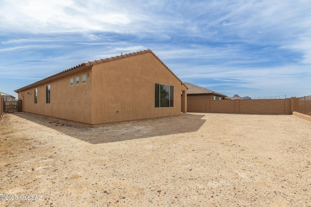 view of property exterior featuring a fenced backyard, a tiled roof, and stucco siding