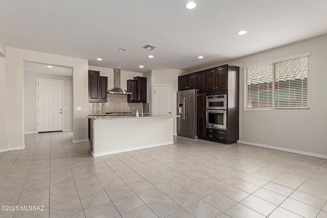 kitchen featuring dark brown cabinetry, stainless steel appliances, visible vents, wall chimney range hood, and tasteful backsplash