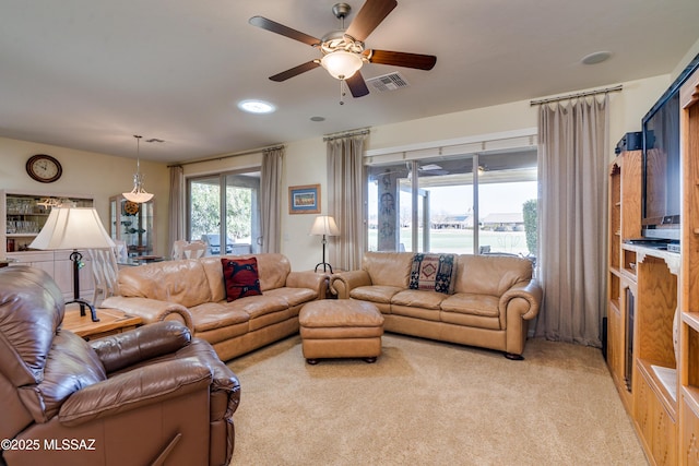 living area with a ceiling fan, light colored carpet, and visible vents