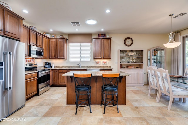 kitchen featuring appliances with stainless steel finishes, a breakfast bar, visible vents, and light stone countertops