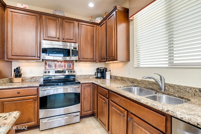 kitchen featuring light tile patterned floors, recessed lighting, stainless steel appliances, a sink, and light stone countertops