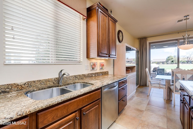 kitchen featuring light stone counters, a sink, dishwasher, brown cabinetry, and decorative light fixtures