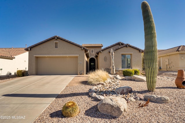 mediterranean / spanish home featuring a garage, concrete driveway, a tile roof, and stucco siding