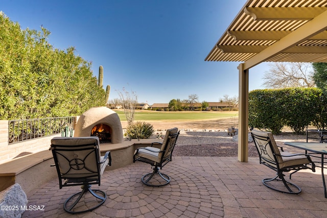 view of patio with a warm lit fireplace and a pergola