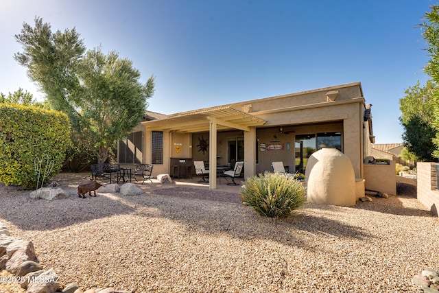 rear view of house featuring stucco siding, a pergola, and a patio