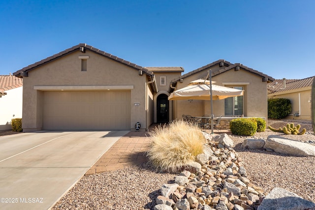 view of front facade with concrete driveway, an attached garage, a tiled roof, and stucco siding