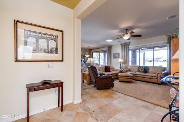 living area featuring a ceiling fan and baseboards