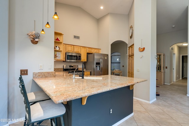 kitchen featuring a kitchen breakfast bar, visible vents, arched walkways, and stainless steel appliances