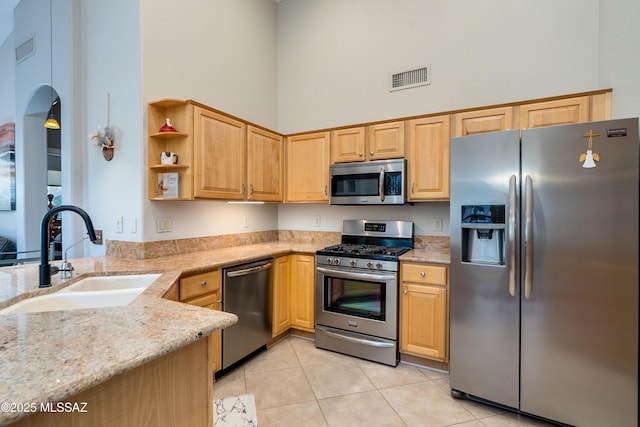 kitchen featuring visible vents, a sink, appliances with stainless steel finishes, light tile patterned floors, and a towering ceiling