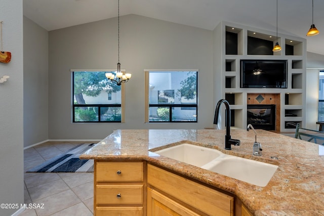 kitchen with light stone counters, built in shelves, light tile patterned floors, lofted ceiling, and a sink