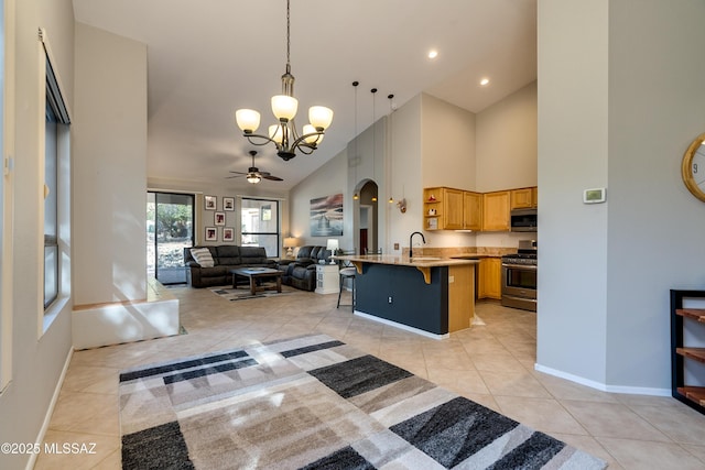 kitchen featuring a breakfast bar area, light tile patterned flooring, arched walkways, appliances with stainless steel finishes, and open floor plan