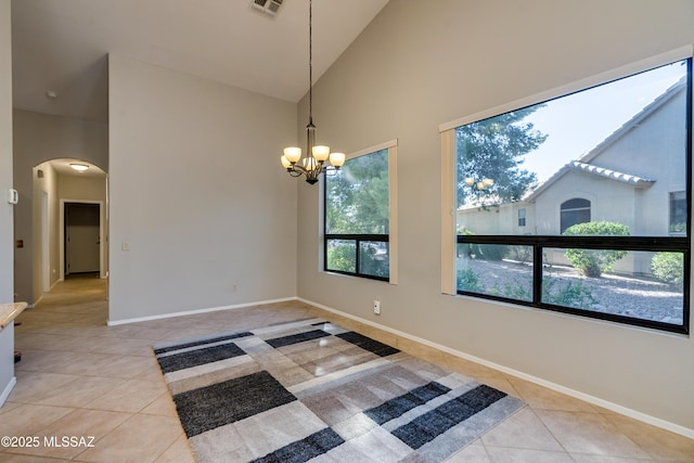 spare room with arched walkways, light tile patterned floors, high vaulted ceiling, and a chandelier