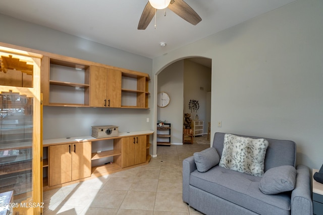 home office featuring arched walkways, a ceiling fan, and light tile patterned flooring