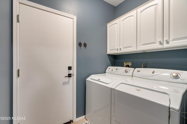 washroom featuring washing machine and clothes dryer, cabinet space, and baseboards