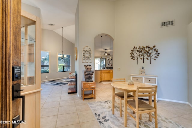 dining area featuring light tile patterned floors, visible vents, baseboards, and high vaulted ceiling